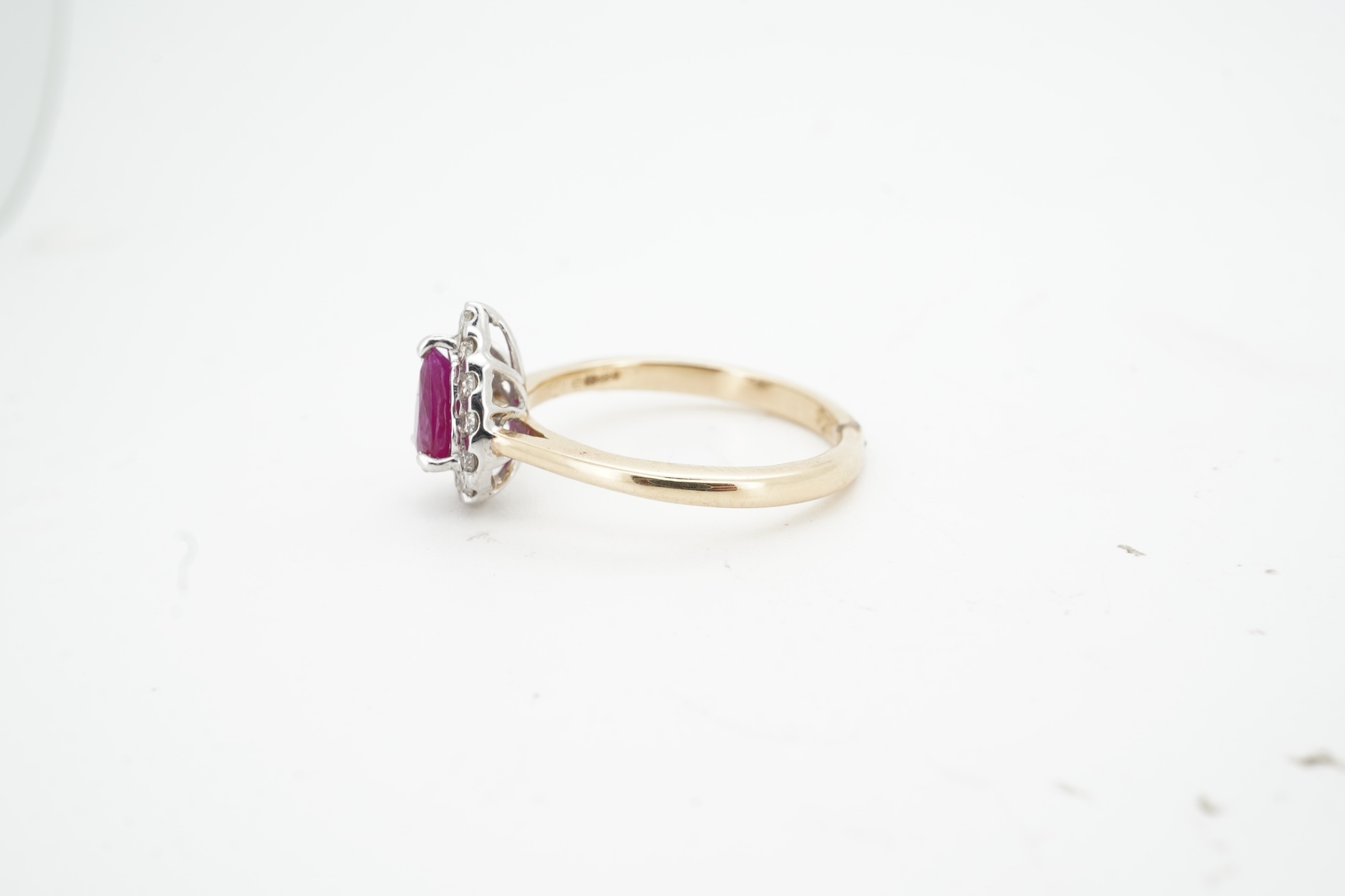 A ruby and diamond cluster ring, claw-set with a pear-shaped ruby weighing approximately 0.60 carats, within a border of brilliant-cut diamonds totalling approximately 0.42 carats, mounted in 14ct gold, size N, British h